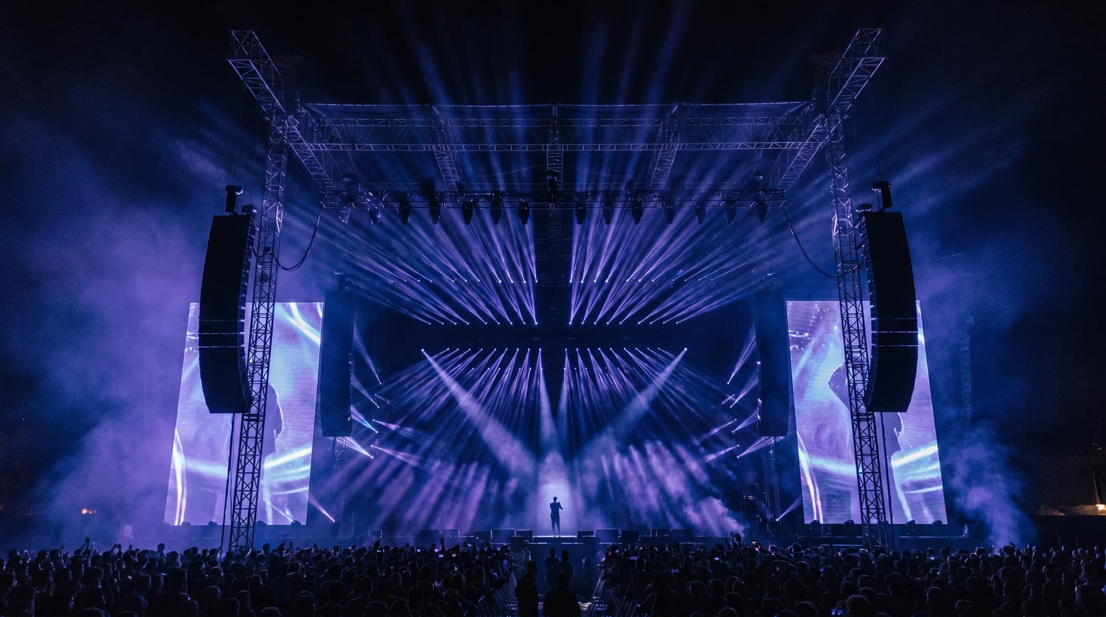 A massive SSOUNDS concert stage lit with hundreds of beams and flanked by line-array systems